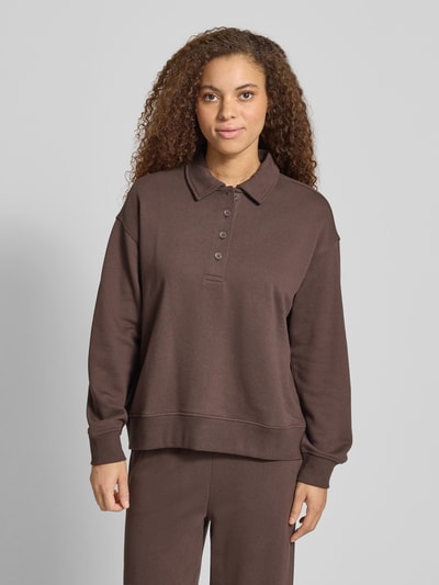 Vrouwenmodel draagt 'Sweatshirt mit Polokragen und Knopfleiste' van Gina Tricot in bruin, regular fit, polokraag, lange mouwen, detailopname bovenlichaam.