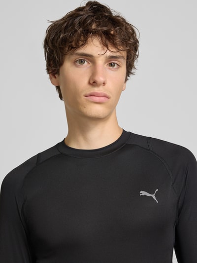 Männermodel trägt schwarzes Slim Fit Sport-T-Shirt mit Logo-Print Modell 'PWRMODE' von PUMA Performance, Nahaufnahme Oberkörper.