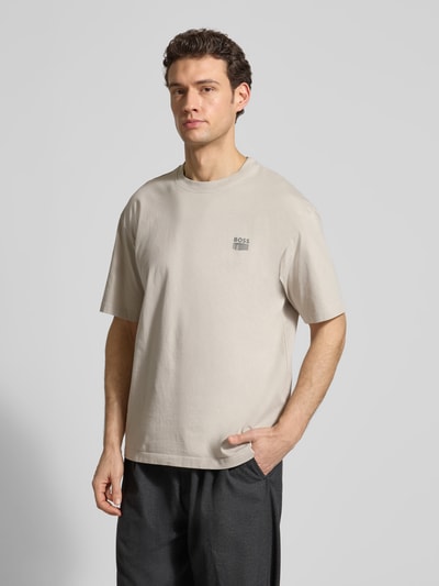 Męski model nosi Regular Fit T-Shirt aus reiner Baumwolle Modell 'TE-BRUTALISM' von BOSS Orange, jasny beż, gładka faktura, krótki rękaw, okrągły dekolt, label-aplikacja, krój regular fit, bawełna, widok całej sylwetki z przodu.