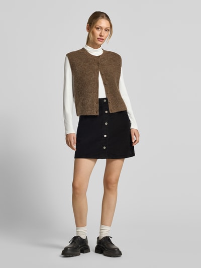 Kobiece model prezentuje Regular Fit Mini-Rock aus Baumwoll-Mix model 'ETTA' od VERO MODA, czarny kolor, guziki z przodu, dama spódnica mini, Ganzkörperansicht von vorne.