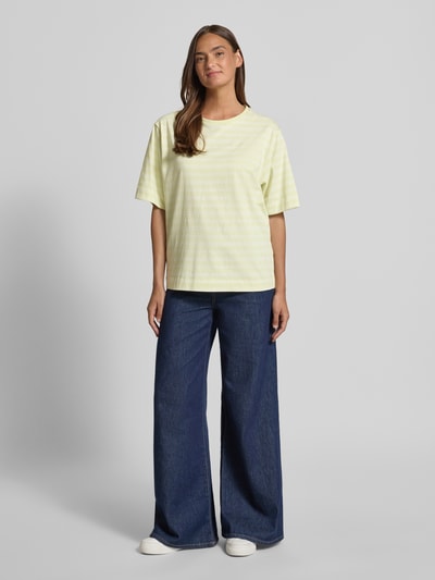 Frauenmodel trägt Oversized Damen T-Shirt aus reiner Baumwolle Modell 'C_EREGULAR_STRIPE' von BOSS Orange mit Allover-Muster, Rundhals, kurzarm, Streifen-Muster, Label-Stitching-Applikation, Jersey-Material in Hellgelb; Ganzkörperansicht von vorne.