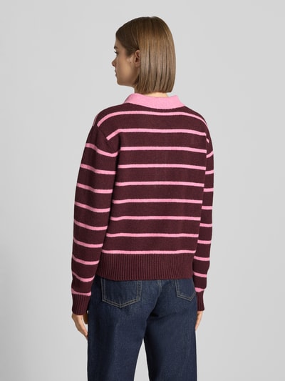 Kobiece modelka nosi sweter z dzianiny Strickpullover z kołnierzykiem polo Model 'RUBY' od JJXX, mieszanka materiałów z bawełną, luźny krój, prążkowane wykończenia, różowe i bordowe paski, długość tyłu w rozmiarze S: 48 cm, długość rękawa: 59 cm, widok całej sylwetki od tyłu.