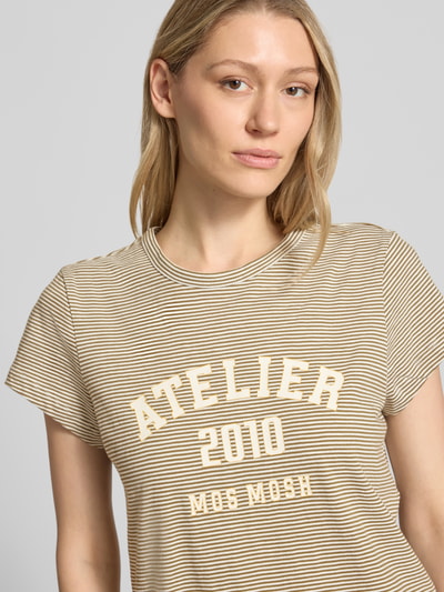 Frauenmodel trägt Regular Fit T-Shirt mit Logo-Print Modell 'Camp' von MOS MOSH aus reiner Baumwolle, beige-weiß gestreift, Rundhalsausschnitt, Nahaufnahme Oberkörper.