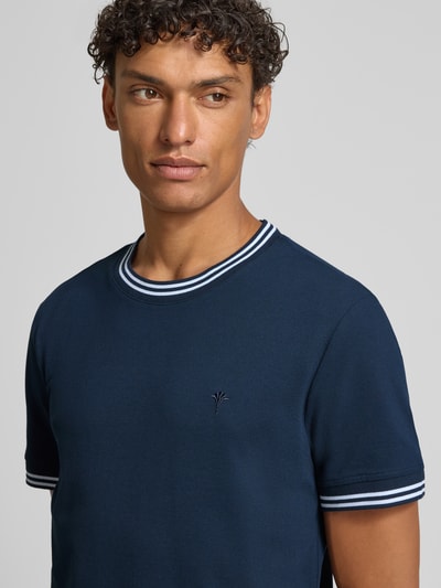 Männermodel trägt T-Shirt mit Kontraststreifen Modell 'Jose' von JOOP! Collection aus Baumwoll-Elasthan-Mix in Dunkelblau, Nahaufnahme Oberkörper.