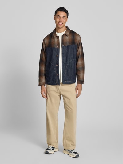 Männermodel trägt Slim Fit Hemdjacke aus reiner Baumwolle von Replay in Denim-Optik mit Umlegekragen und Eingrifftaschen, Ganzkörperansicht von vorne.