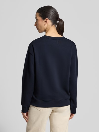 Frauenmodel trägt Sweatshirt mit Label-Stitching und Rundhalsausschnitt von Gant in Dunkelblau, reine Baumwolle, Loose Fit, gerippte Abschlüsse, Ganzkörperansicht Rückansicht.