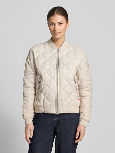 Frauenmodel trägt Steppjacke mit Zweiwege-Reißverschluss Modell 'BOY' von Frieda & Freddies in Beige mit Rautensteppung, Ganzkörperansicht von vorne. Regular Fit, Stehkragen, Reißverschlusstaschen, strukturierte Oberfläche. Rückenlänge, Schulterbreite, Brustweite und Ärmellänge in Größe 36: 20 cm, 16 cm, 21 cm, 24 cm.