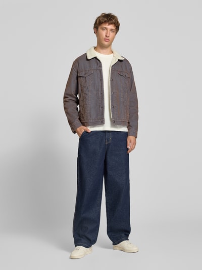 Männermodel trägt Relaxed Fit Jeansjacke aus Baumwoll-Mix von Levi's®, dezente Blautöne, Struktur durch Steppnähte, Ganzkörperansicht von vorne.