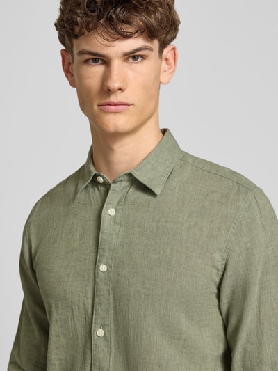 Männermodel trägt Slim Fit Freizeithemd aus Baumwoll-Leinen-Mix Modell 'CAIDENLS SOLID' von Only & Sons in Grün, Optik: Unifarben, Flammgarn-Struktur, Nahaufnahme Oberkörper.