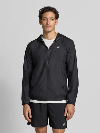 Männermodel trägt schwarze Regular Fit Trainingsjacke mit Logo-Print Modell 'Core' von ASICS TIGER, leichte Struktur, Ganzkörperansicht von vorne.