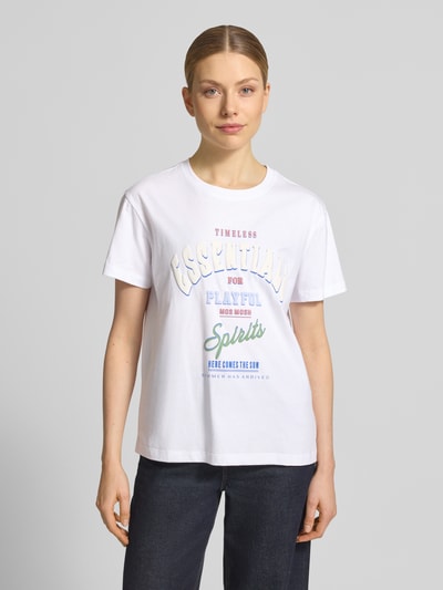 Frauenmodel trägt T-Shirt mit Rundhalsausschnitt Modell 'Raft' von MOS MOSH aus reiner Baumwolle, weiß mit Label-Print, Ganzkörperansicht von vorne.