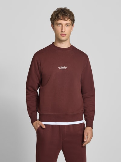 Männermodel trägt Regular fit sweatshirt aus katoenmix Model 'Soho' von JACK & JONES, logoprint, ronde hals, elastische boordjes, ganzkörperansicht von vorne. Ruglengte maat M: 65 cm, mouwlengte maat M: 66 cm.