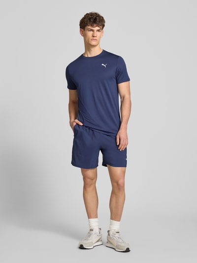 Männermodel trägt Regular Fit T-Shirt mit Logo-Print Modell 'Solid' von PUMA PERFORMANCE in Dunkelblau, Ganzkörperansicht von vorne.