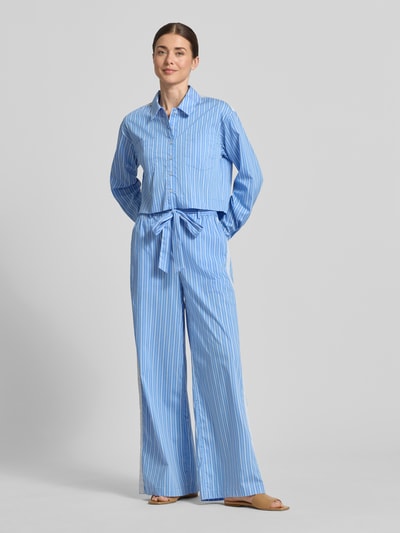 Vrouwenmodel draagt blouse met borstzakken model 'Dana' van GUIDO MARIA KRETSCHMER WOMAN in blauw-wit katoenmix met stretch, regular fit, overhemdkraag, knoopsluiting, sportmanchetten, ruglengte 52 cm, mouwlengte 59 cm, verticale strepen, gladde textuur, geheelbeeld van voren