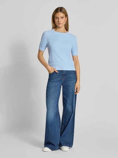 Frauenmodel trägt Regular Fit Strickpullover aus Viskose-Baumwoll-Mix Modell 'ELINNA' von Selected Femme in Hellblau, strukturierte Optik, Kurzarm, Rundhals, uni, Ganzkörperansicht von vorne.