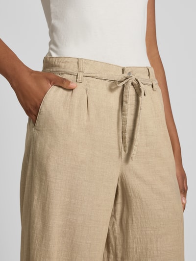 Frauenmodel trägt Wide Fit Stoffhose mit Bügelfalten Modell 'Livia' von Angels aus Reine Baumwolle in Beige mit Eingriffstaschen, Nahaufnahme Oberkörper.