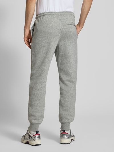 Männermodel trägt Sweatpants mit Label-Stitching und Gesäßtasche von Nike aus Baumwoll-Mix, Regular-Fit, grau meliert, Ganzkörperansicht Rückansicht.