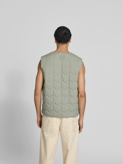 Männermodel trägt Regular Fit Weste in Stepp-Optik von MAISON KITSUNÉ in hellem Grün mit Eingrifftaschen, Rückansicht, Rückenlänge 68 cm.