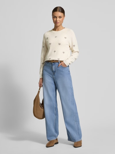 Vrouwenmodel draagt Regular Fit gebreide pullover met Intarsia model 'DOFFY INTARSIA' van Vero Moda in effen look met all-over motief, applicatie met labelstitching, ronde hals, lange mouwen, geribde mouwboord en rompzoom, materiaalverwerking knitwear. Volledige lichaamsaanzicht van voren.