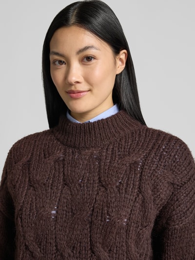 Frauenmodel trägt Regular Fit Pullover mit Rundhalsausschnitt Modell 'MAYBE' von VERO MODA in Dunkelbraun mit grober Stricktextur, Nahaufnahme Oberkörper.