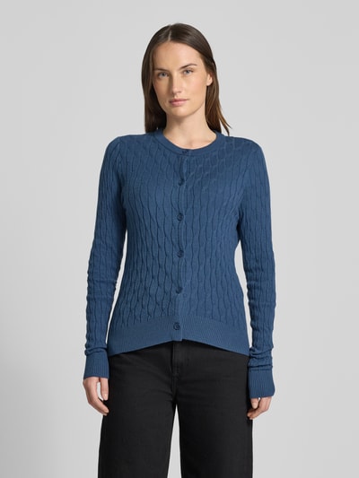 Frauenmodel trägt Regular Fit Strickjacke mit Viskose-Anteil Modell 'FANTASTIC' von Vero Moda in Unifarben mit Zopfmuster und Rundhals, Ganzkörperansicht von vorne.