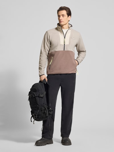 Männermodel trägt Fleecepullover mit Stehkragen und Reißverschluss von Columbia, Regular-Fit, Label-Patch, Reißverschlusstaschen, beige und braun, Rückenlänge 70 cm, Ärmellänge 67 cm, Ganzkörperansicht von vorne.