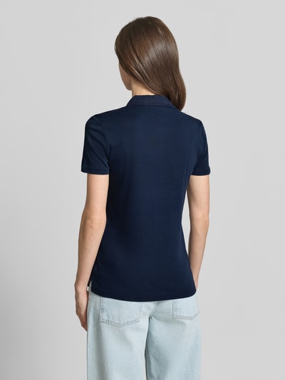 Modelka kobieca nosi Regular Fit Poloshirt aus reiner Baumwolle od Tom Tailor, jednolity granatowy kolor, krótki rękaw, jersey, widok całego ciała z tyłu.