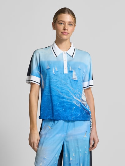 Frauenmodel trägt Regular Fit Bluse aus reinem Lyocell mit Polokragen von Marc Cain, Allover-Motiv-Print in Blau und Weiß, Kurzarm, Tunnelzug im Bund, fließende Textur, maritimes Motiv, Ganzkörperansicht von vorne.