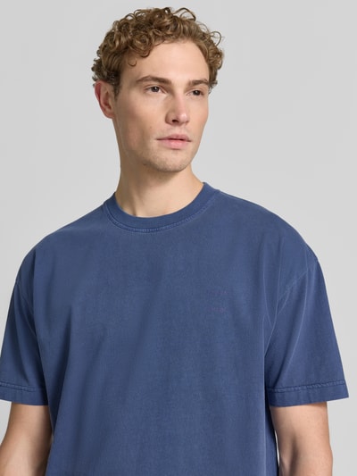 Mężczyznamodel nosi męski t-shirt z bawełny, krój regular fit, model 'JOEL' od Samsøe Samsøe, okrągły dekolt, długość tyłu 72 cm, rozmiar M. Zbliżenie na górną część ciała z przodu.
