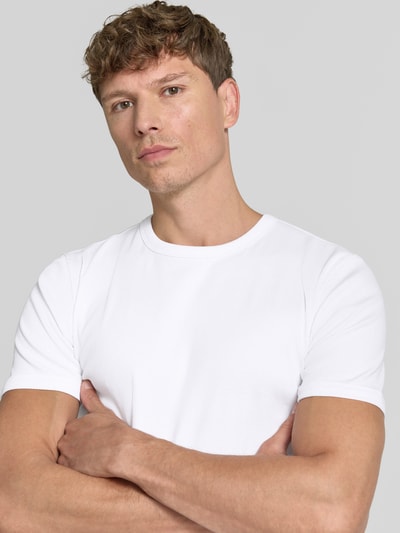 Męski model nosi T-Shirt in Ripp-Optik mit Rundhalsausschnitt od Jake*s, mieszanka bawełny i elastanu, krój slim fit, długość tyłu w rozmiarze M: 56 cm, biała gładka tekstura, prosty fason, Nahaufnahme górnej części ciała.