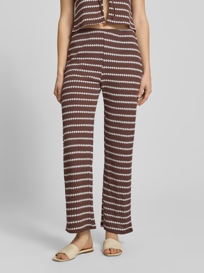 Frauenmodel trägt Loose Fit Stoffhose mit Baumwoll-Anteil Modell 'EVA LIFE' von Only, braun-weißes Allover-Muster, strukturierte Strickoptik, elastischer Bund, Ganzkörperansicht von vorne.