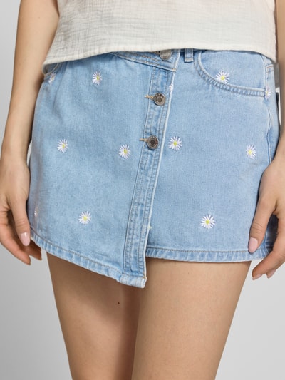 Frauenmodel trägt Regular Fit Skort aus reiner Baumwolle Modell 'LESLY' von Only in hellblauer Denim-Optik mit Stickerei, Nahaufnahme Oberkörper.
