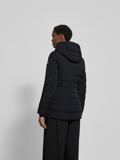 Frauenmodel trägt Daunenjacke mit Kapuze von Moose Knuckles, Schwarz, Material-Mix mit Stretch-Anteil, taillierter Schnitt, Reißverschluss, Reißverschlusstaschen, Rückenlänge 75 cm, Brustweite 48 cm, Ärmellänge 65 cm, Ganzkörperansicht Rückansicht.