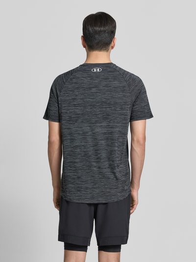 Männermodel trägt T-Shirt mit Label-Print Modell 'Tech' von Under Armour in Anthrazit mit melierter Struktur, gerader Schnitt, Rückenlänge 75 cm, Ganzkörperansicht Rückansicht.
