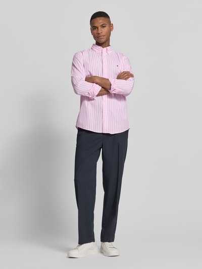 Männermodel trägt Regular Fit Freizeithemd aus Baumwoll-Popeline von Tommy Hilfiger mit Allover-Muster, gestreift, Ganzkörperansicht von vorne.