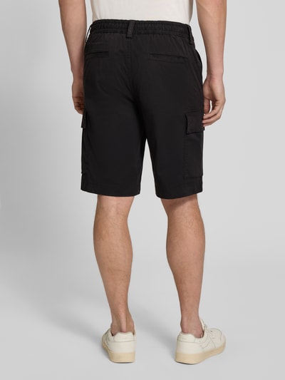 Männermodel trägt Relaxed Fit Cargoshorts aus Baumwoll-Mix Modell 'SISLA' von BOSS Orange, unifarben, Label Patch, Ganzkörperansicht Rückansicht.