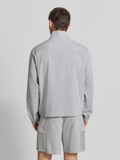 Männermodel trägt Regular fit jack met opstaande kraag Model 'Unstoppable' van Under Armour in lichtgrijs, elastische mouwboorden, ruglengte maat M 67 cm, mouwlengte maat M 64 cm, elastische materiaalmix, ganzkörperansicht rugaanzicht.
