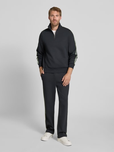 Männermodel trägt Flared Fit Sweatpants aus Baumwoll-Mix von Paul Smith in Dunkelgrau mit elastischem Bund, Ganzkörperansicht von vorne. Herren Sweatpants mit Gesäßtasche, Innenbeinlänge 77 cm.