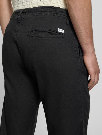 Männermodel trägt schwarze Relaxed Fit Hose aus Baumwoll-Leinen-Mix Modell 'KANE' von Jack & Jones, elastischer Bund, Detailaufnahme Rückansicht.
