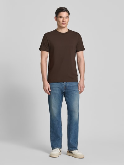 Mężczyzna nosi T-shirt z okrągłym dekoltem model 'Carlonito' od JOOP! Collection, kolor brązowy, bawełniany miks ze stretchem, krój straight fit, długość tyłu w rozmiarze M: 71 cm, zdjęcie całej sylwetki z przodu.