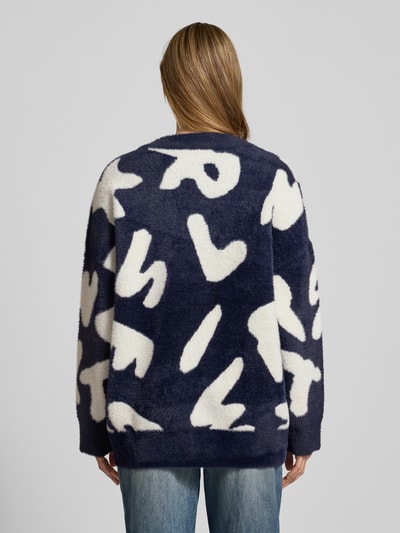 Frauenmodel trägt Comfort Fit Strickjacke mit Allover-Muster Modell 'JARDEN' von Essentiel Antwerp in Dunkelblau und Weiß, Materialverarbeitung: Strick, Ganzkörperansicht Rückansicht.