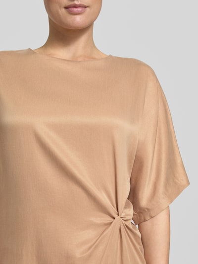 Frauenmodel trägt Midikleid mit Knotendetail Modell 'INDAH' von Drykorn aus Cupro-Baumwoll-Mix in Beige, Gerader-Schnitt, Rundhalsausschnitt, Detailaufnahme Oberkörper.