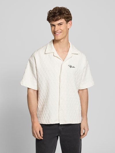 Männermodel trägt Regular Fit Freizeithemd mit Label-Stitching Modell 'Jovren' von Pegador, Reverskragen, Elastischer-Material-Mix, Halbarm, Knopfleiste, helle Farbe, strukturierte Oberfläche, Nahaufnahme Oberkörper. Rückenlänge bei Größe M: 72 cm, Schulterbreite: 45 cm, Ärmellänge: 33 cm.