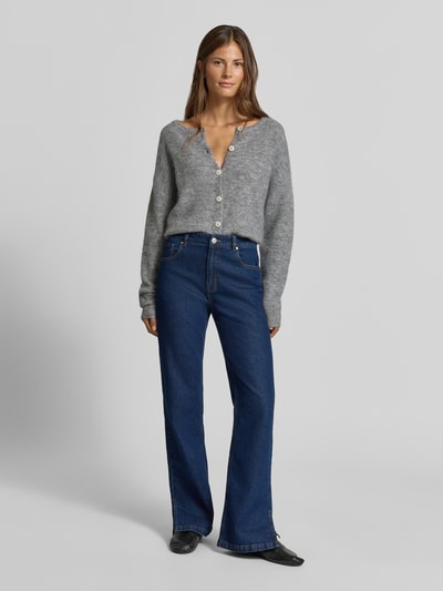 Vrouwenmodel draagt Strickjacke met Woll-Anteil van MYON, grijs met riblook, recht pasvorm, ronde hals, doorlopende knoopsluiting, dames, elastische materiaalmix, oversneden schouders, ruglengte maat 36: 50 cm, mouwlengte maat 36: 67 cm, volledige lichaamsaanzicht van voren.