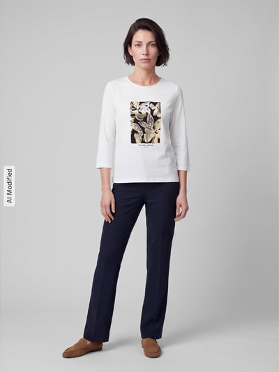 Frauenmodel trägt 3/4-Shirt mit Frontprint von TOM TAILOR, weiß mit Motiv-Print, Regular Fit, 3/4-Arm, schlichte Hose, Ganzkörperansicht von vorne, KI-modifiziertes Bild.
