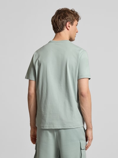 Männermodel trägt T-Shirt mit Logo und Rundhalsausschnitt von CHAMPION aus reiner Baumwolle im Regular-Fit mit Label-Stitching, Ganzkörperansicht Rückansicht.