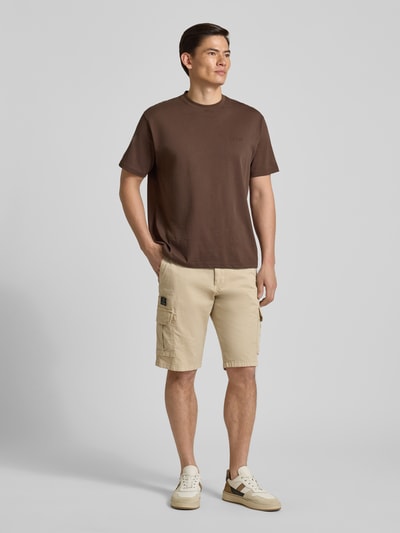 Männermodel trägt Bermudas mit Cargotaschen von bugatti in Beige, Regular Fit, Knopf- und Reißverschluss, Ganzkörperansicht von vorne.
