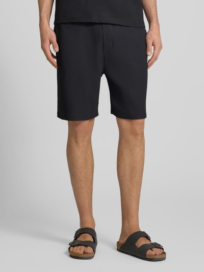 Männermodel trägt Shorts in Plissee-Optik mit elastischem Bund von REVIEW, schwarz, Material-Mix mit Stretch-Anteil, Regular-Fit, Nahaufnahme Unterkörper.