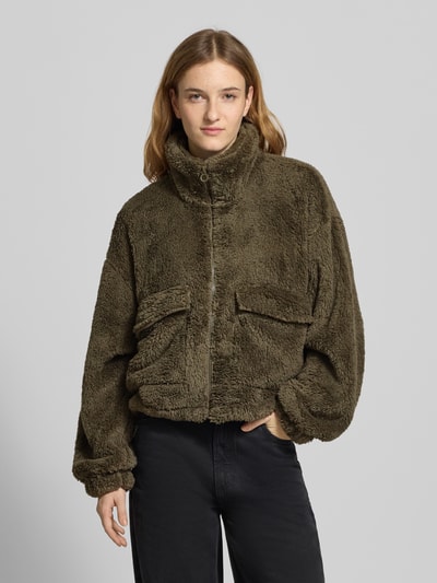 Frauenmodel trägt Loose Fit Fleecejacke mit Stehkragen Modell 'ANNA CONTACT' von Only in Oliv, Kunstwebfell, Tunnelzug, Ganzkörperansicht von vorne.