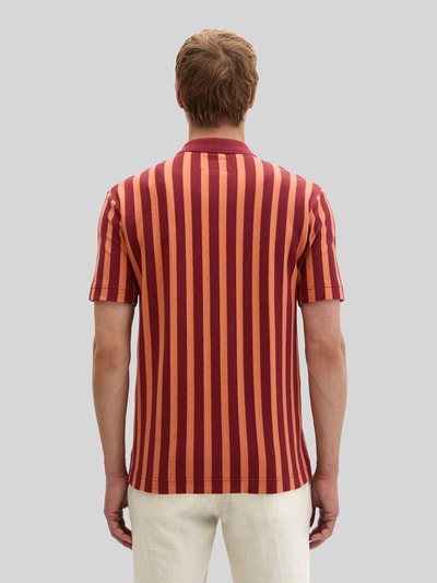 Männermodel trägt Regular Fit Freizeithemd aus reiner Baumwolle von Marc O'Polo in rot-orange gestreifter Strickoptik, Ganzkörperansicht Rückansicht.